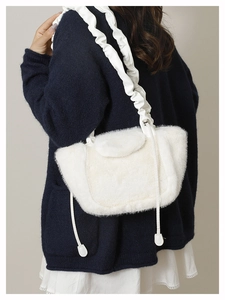 Detailed view of plush faux fur handbag with stylish pleated shoulder strap on model