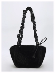 Detailed close-up of fluffy black plush fabric and unique pleated scrunchie handle on bag