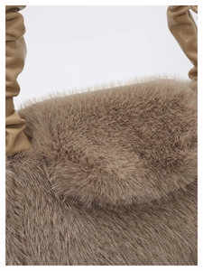 Detailed shot of brown faux fur texture and ruched leather handle on a chic tote bag