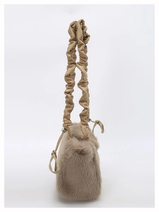 Detail of khaki plush handbag featuring soft faux fur and pleated leather handle texture