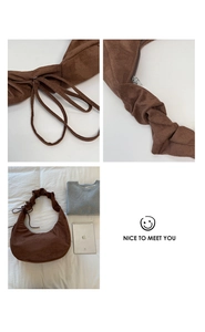 Detail of brown pleated suede shoulder bag with drawstring accents and silver zipper