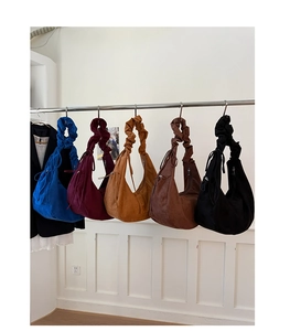 Macro detail of high-capacity suede hobo bags showing scrunched straps in multiple colors