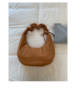 Detailed view of brown suede half-moon bag featuring pleated straps and drawstring accents