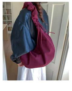 Macro detail of wine red suede hobo bag with pleated shoulder strap and drawstring closure