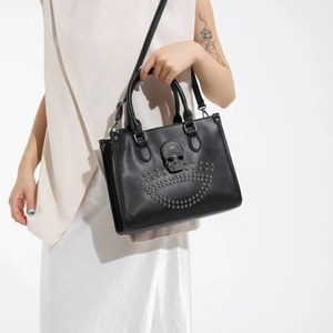 Chic black tote bag with vintage metal skull and decorative studs in punk style