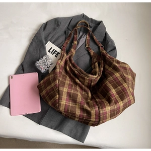 Détail à plat d'un cabas à carreaux marron sur un costume gris avec accessoires