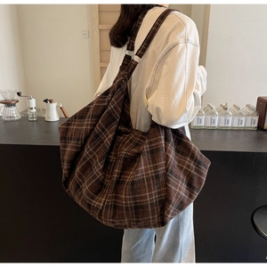 Gros plan sur la texture du tissu écossais marron et la bandoulière large du sac cabas