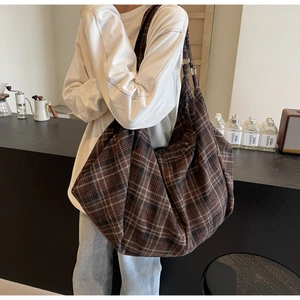 Gros plan d'un grand sac cabas à carreaux marron porté à l'épaule par un mannequin
