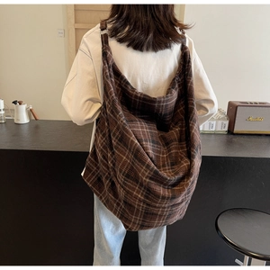 Gros plan d'un grand sac cabas en tissu à carreaux marron porté à l'épaule