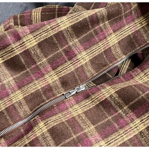 Détail du tissu à carreaux et fermeture éclair argentée sur un sac cabas marron