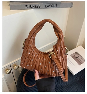 Detail of caramel pleated handbag with quilted pattern and sparkling rhinestone accents