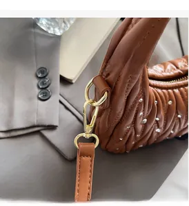 Close-up of brown pleated bag with crystal accents and golden luxury hardware
