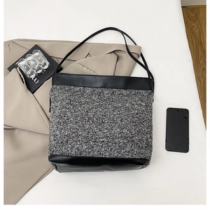Close-up of black and grey tweed tote bag with smooth leather trim and thin straps