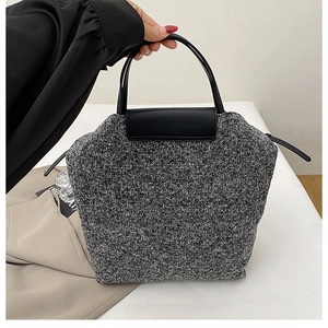 Detail of knit tweed texture and black leather handle on a stylish tote bag