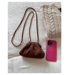 Detail einer dunkelbraunen Wildleder-Mini-Muschel-Tasche mit Faltenverschluss auf weißem Grund