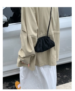 Detail einer schwarzen Falten-Cloud-Tasche als Umhängetasche zu einem beigen Freizeitoutfit