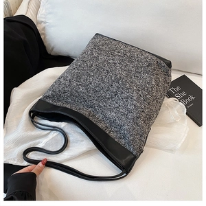 Close-up of textured tweed fabric and black leather stitching on a large tote bag
