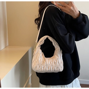 Detalle del bolso de hombro plisado crema con adornos de strass brillantes y elegantes