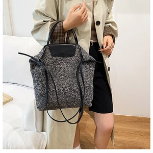Detail of grey wool tote bag with black leather straps and drawstring side feature