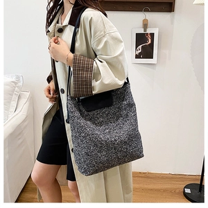Close-up of grey textured woolen tote bag with black leather flap and shoulder strap