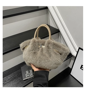 Detail of gray plush faux fur handbag featuring round beige handles and metal clasp