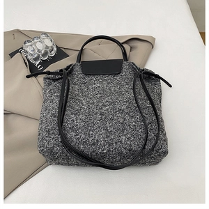 Close-up of black and grey wool blend texture with premium leather strap detail on tote bag