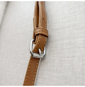Dettaglio del cinturino in pelle marrone con fibbia in metallo e cuciture rifinite