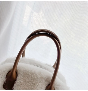 Primo piano della borsa in peluche bianca con dettagli dei manici in pelle marrone