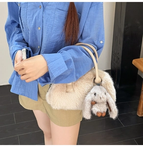 Dettaglio della borsa Boston in peluche bianco sporco con ciondolo a coniglio e manici