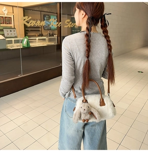 Dettaglio della borsa Boston in pelliccia sintetica bianca con manici in pelle e charm