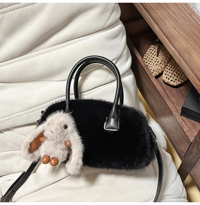 Dettaglio della borsa in peluche nero con ciondolo a coniglio e tracolla in pelle