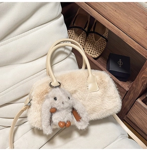 Dettaglio della borsa Boston in peluche crema con ecopelliccia e ciondolo a coniglietto