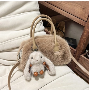 Dettaglio di una borsa in finta pelliccia marrone con ciondolo a coniglio e manici in pelle