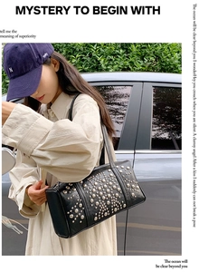 Detailed view of a black leather cylindrical bag featuring silver rivet embellishments