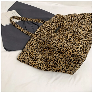 Detailed top view of a large leopard print canvas tote bag on white textured fabric