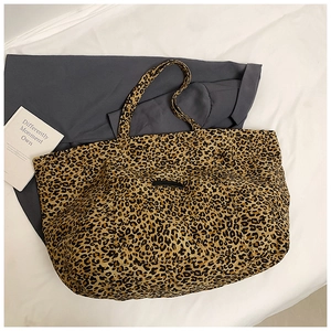 Detailed view of leopard print tote bag with black logo patch and durable straps
