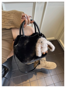 Detail of plush black faux fur handbag with leather handle and cute grey bunny charm