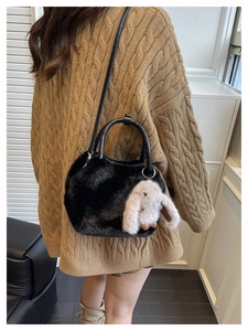Detail of black faux fur handbag with beige bunny charm and black leather handles
