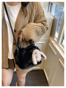 Detail of black faux fur handbag featuring cute white bunny plush pendant and shoulder strap