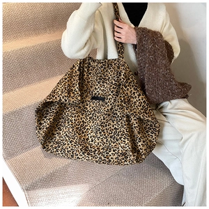Detailed macro view of large leopard print tote bag featuring a black logo label and thin handles