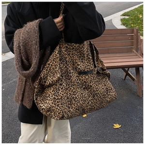 Detailed close-up of leopard print tote bag with black leather label and canvas texture