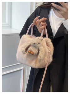 Detail of a pink faux fur handbag with a cute plush long-eared rabbit pendant charm