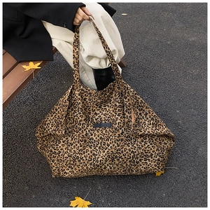 Close-up of leopard print tote bag with black leather tag worn on a shoulder
