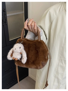 Detailed texture of dark brown faux fur handbag with stylish white rabbit charm accessory