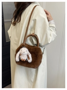 Brown plush handbag detail with cute white bunny charm and leather shoulder strap