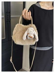 Detail of beige plush handbag with soft faux fur texture and cute rabbit charm accessory
