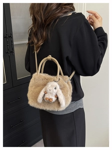 Detailed view of brown plush crossbody bag with cute rabbit doll on black background