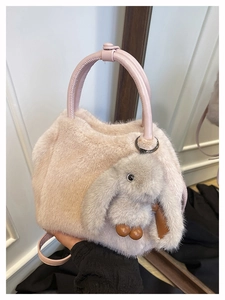 Close-up of soft faux fur handbag featuring a cute plush bunny charm and crossbody strap