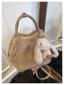 Detail of plush faux fur handbag with leather handles and cute bunny charm accessory