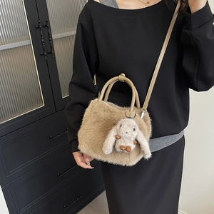 Brown fuzzy plush handbag with cute rabbit pendant and shoulder strap on model